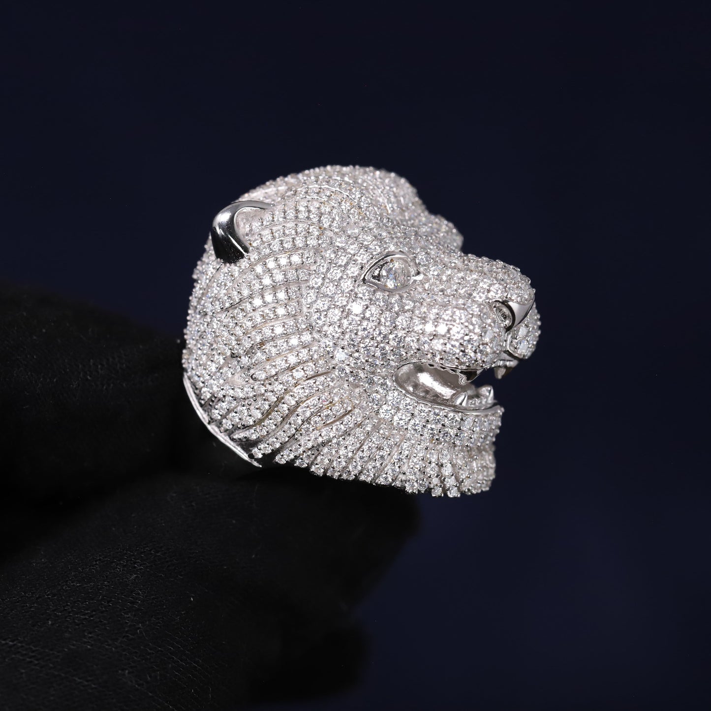 Silver lion head ring with gemstones on a black background