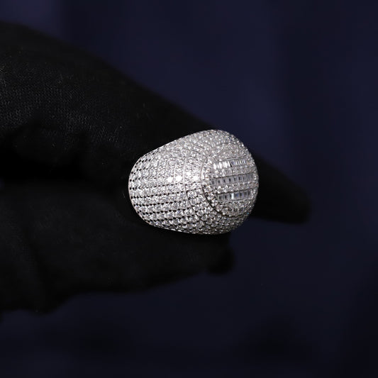 Silver ring with diamonds held by a gloved hand against a dark background