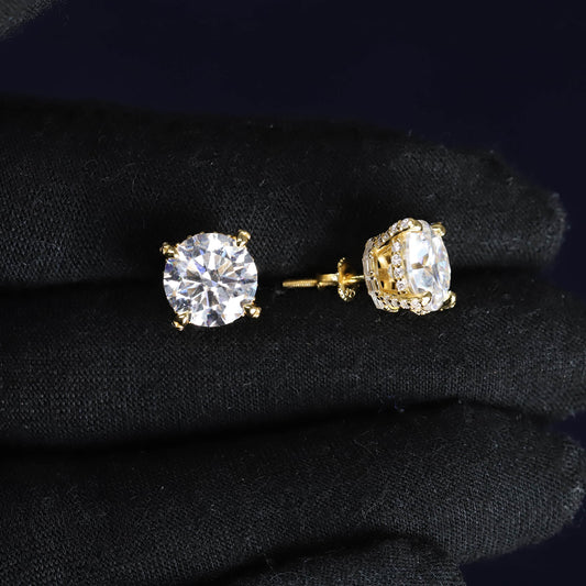 Gold stud earrings with clear gemstones on a black fabric background
