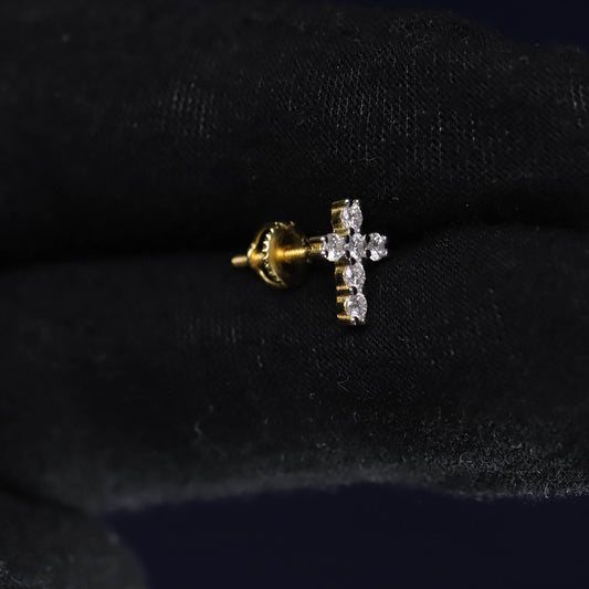 Gold and diamond cross earring on a black background