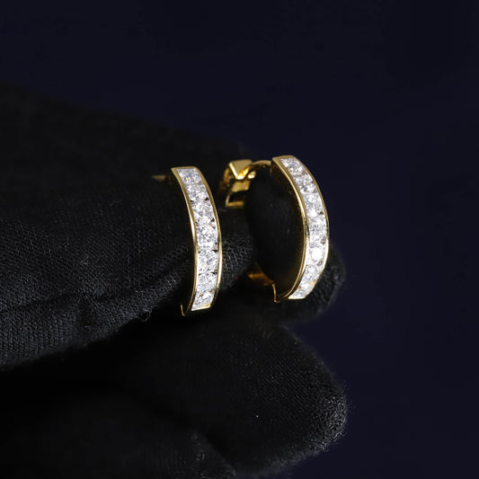 Gold hoop earrings with clear stones on a black surface