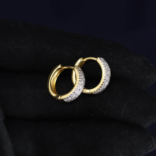Pair of gold hoop earrings with embedded stones on a black background
