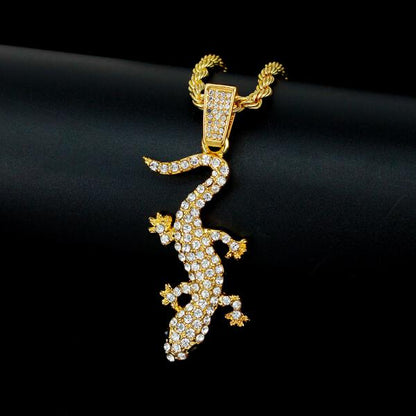 Gold lizard-shaped pendant with gemstones on a black background