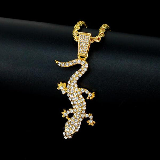 Gold lizard-shaped pendant with gemstones on a black background