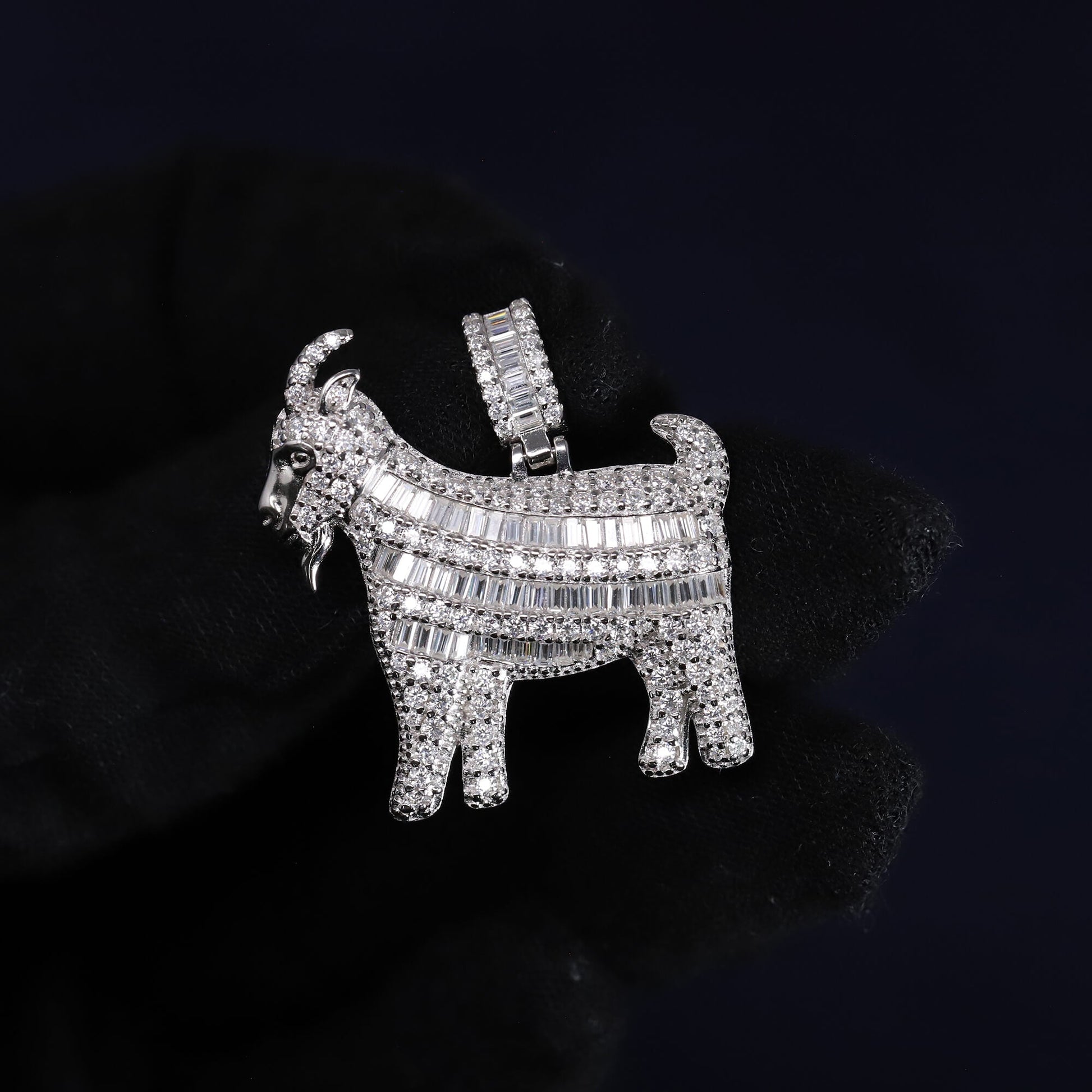 Silver goat-shaped pendant with gemstones on a black background
