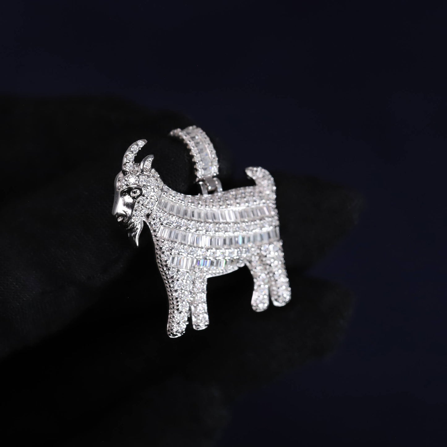 Silver goat-shaped brooch with gemstones on a dark background