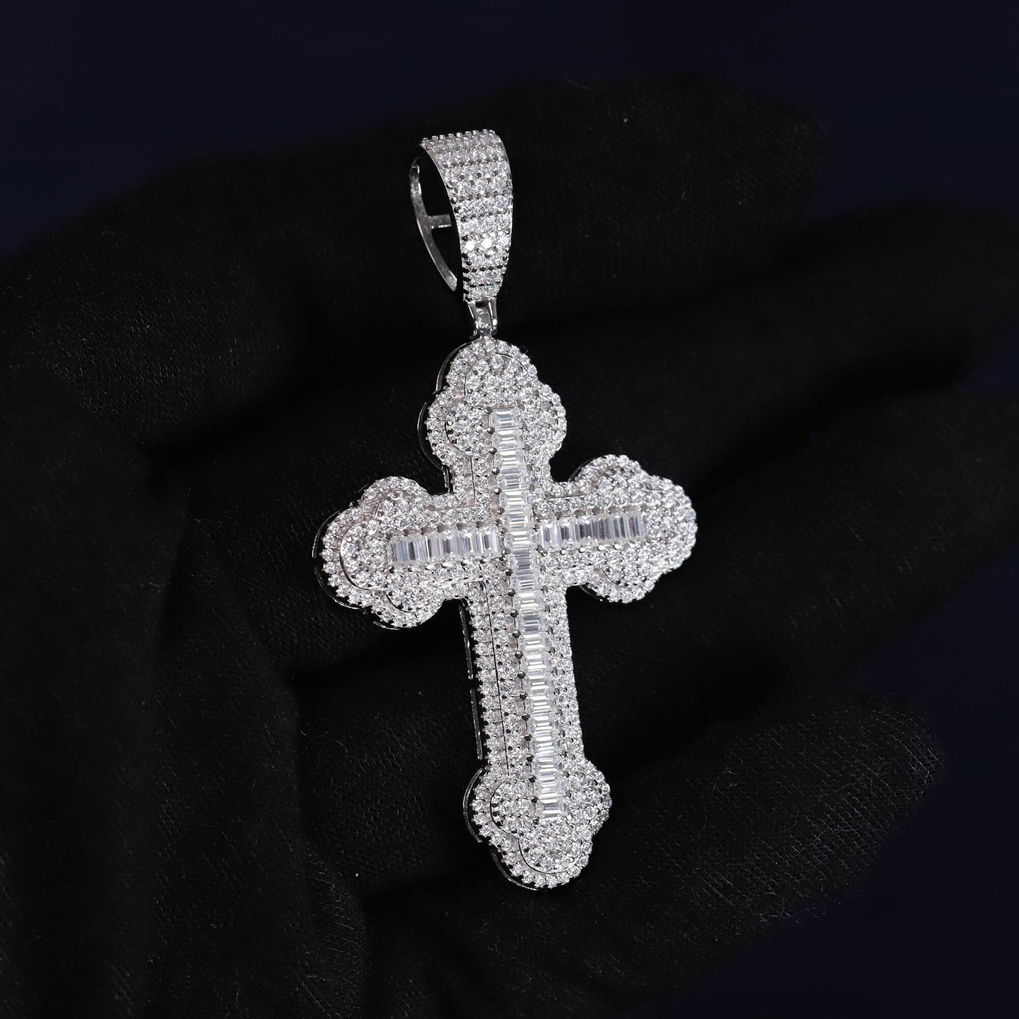 Silver cross pendant with clear stones on a black background
