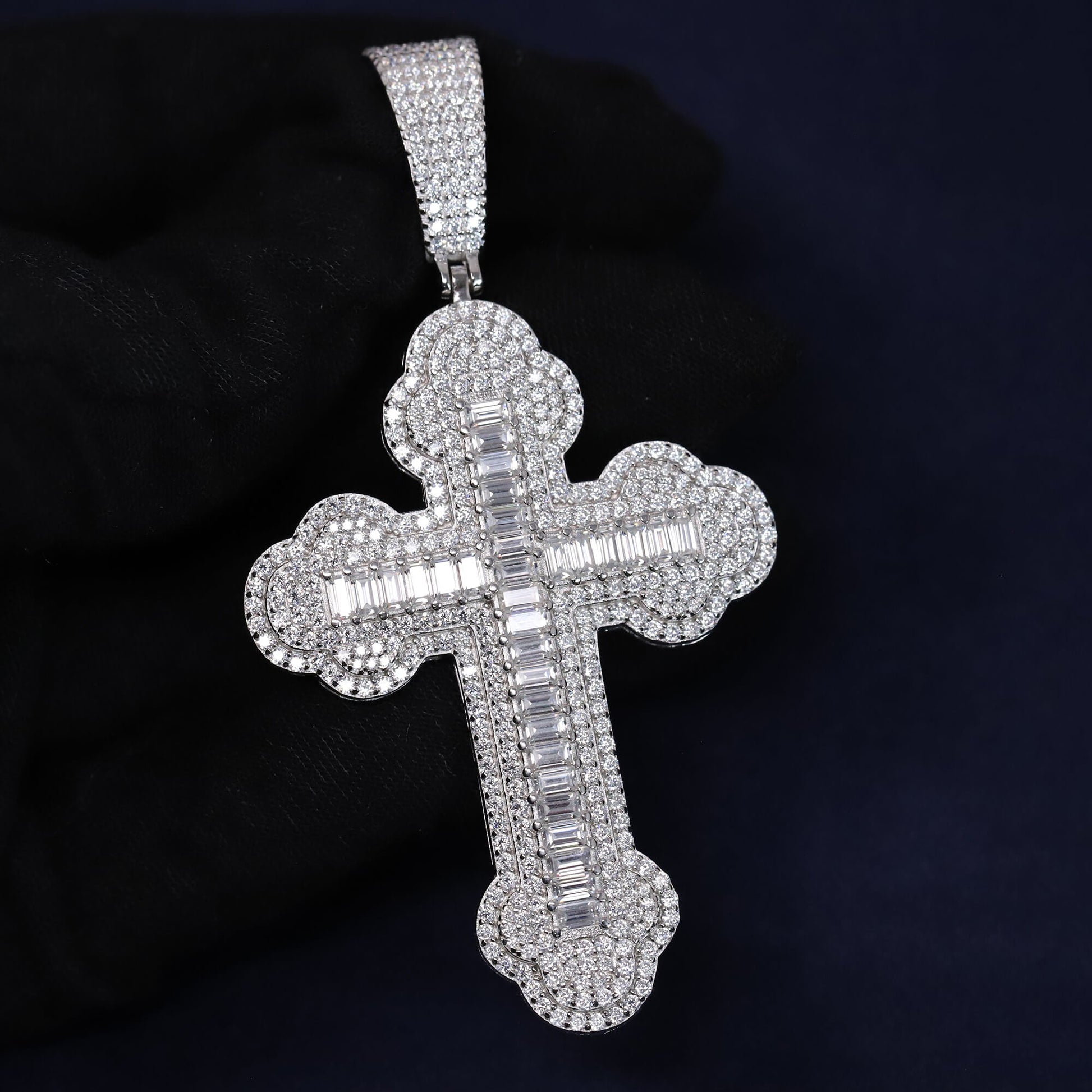 Silver cross pendant with clear stones on a dark background