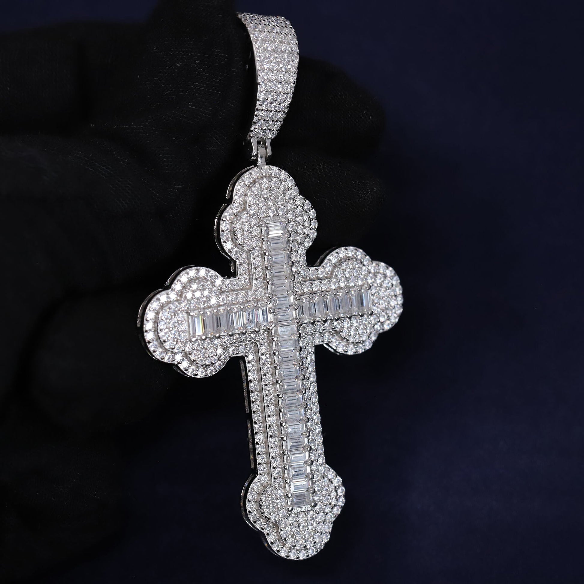 Silver cross pendant with gemstones on a dark background