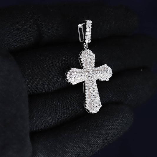 Silver cross pendant with clear stones on a black background