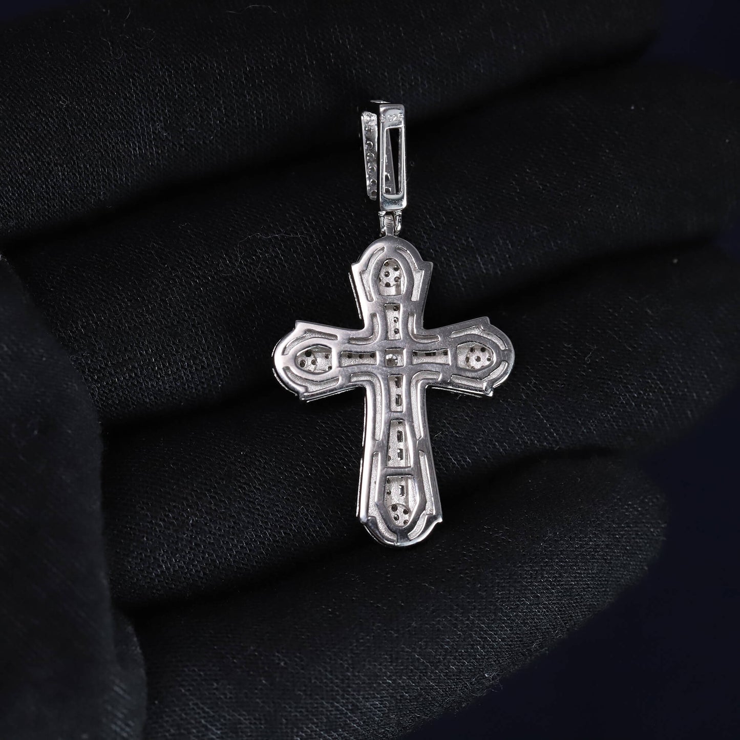 Silver cross pendant on a black fabric background