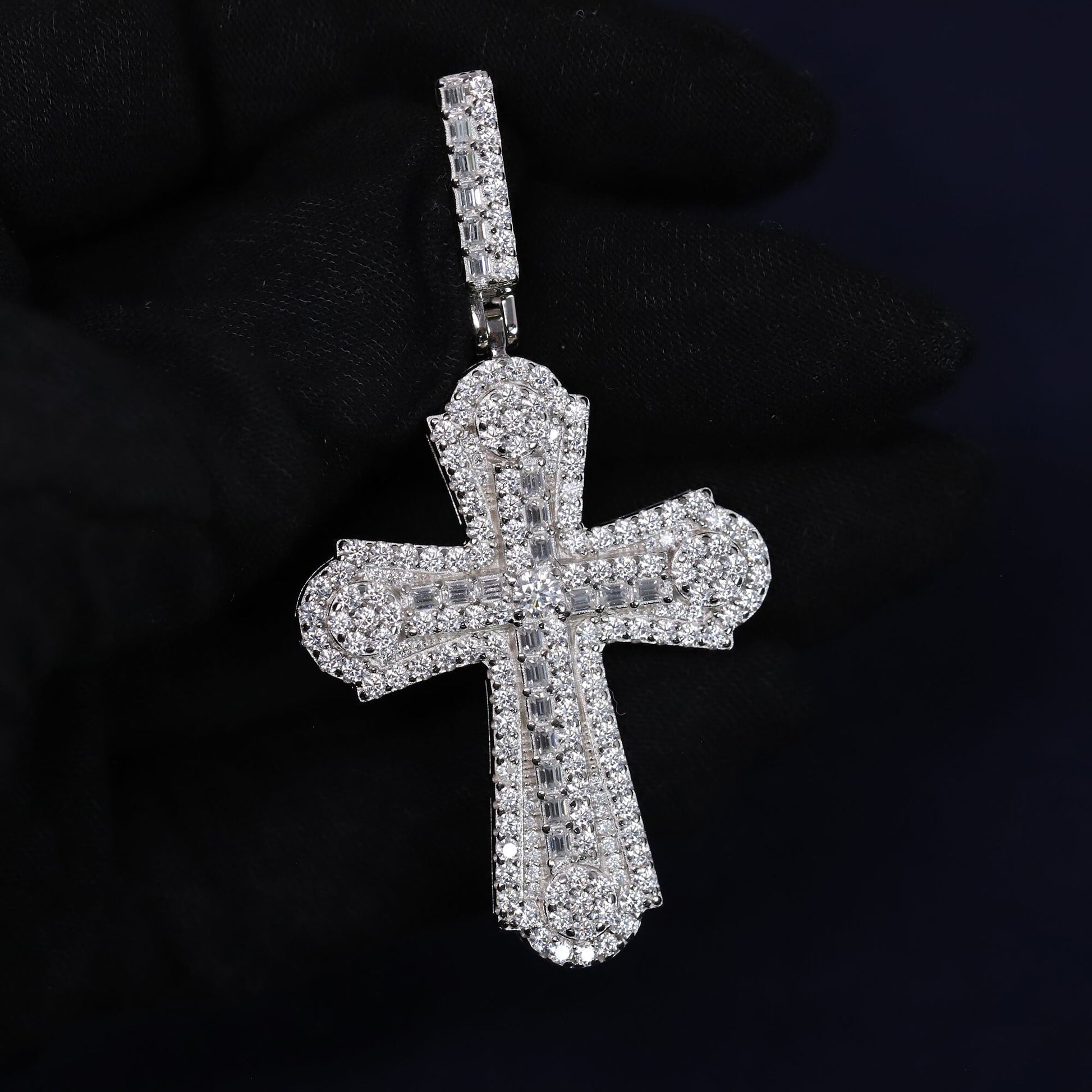 Silver cross pendant with clear stones on a black background