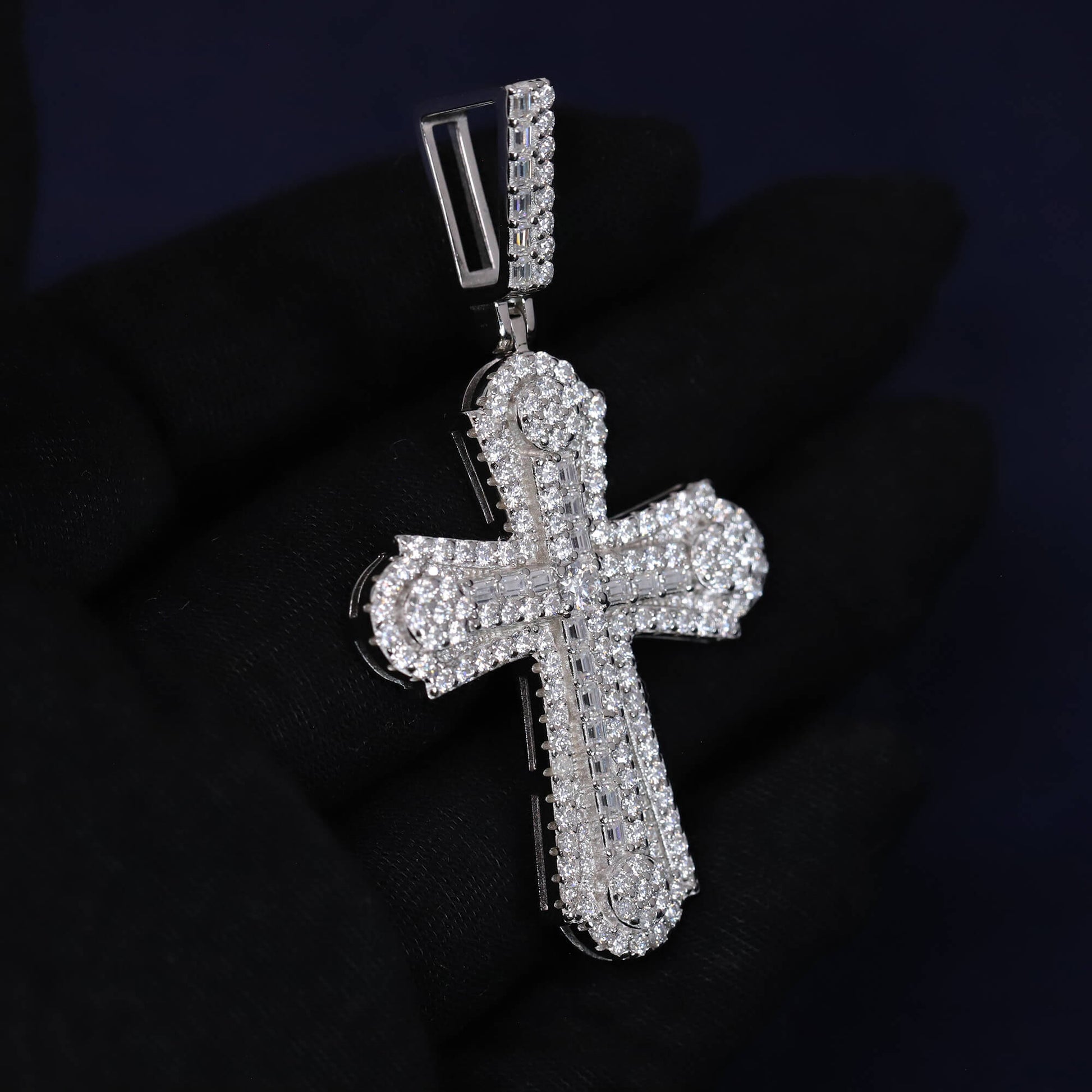 Silver cross pendant with clear stones on a dark background