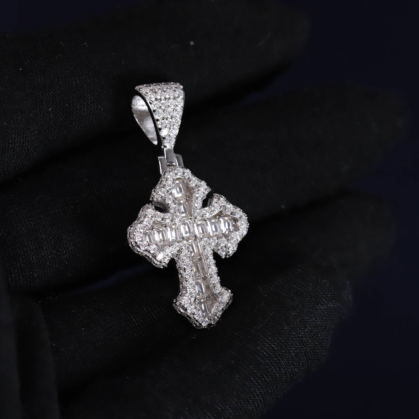 Silver cross pendant with clear stones on a black background