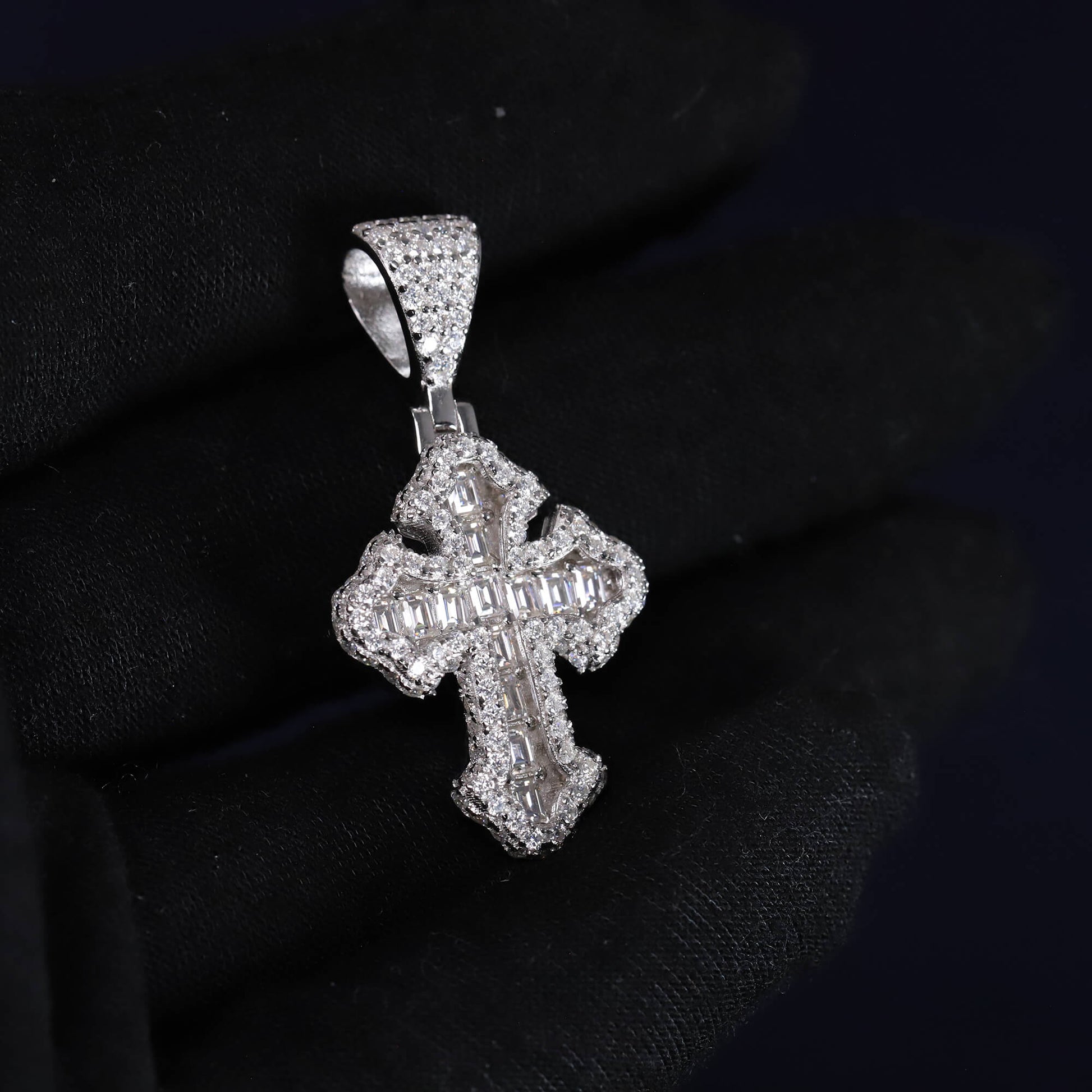 Silver cross pendant with clear stones on a black background