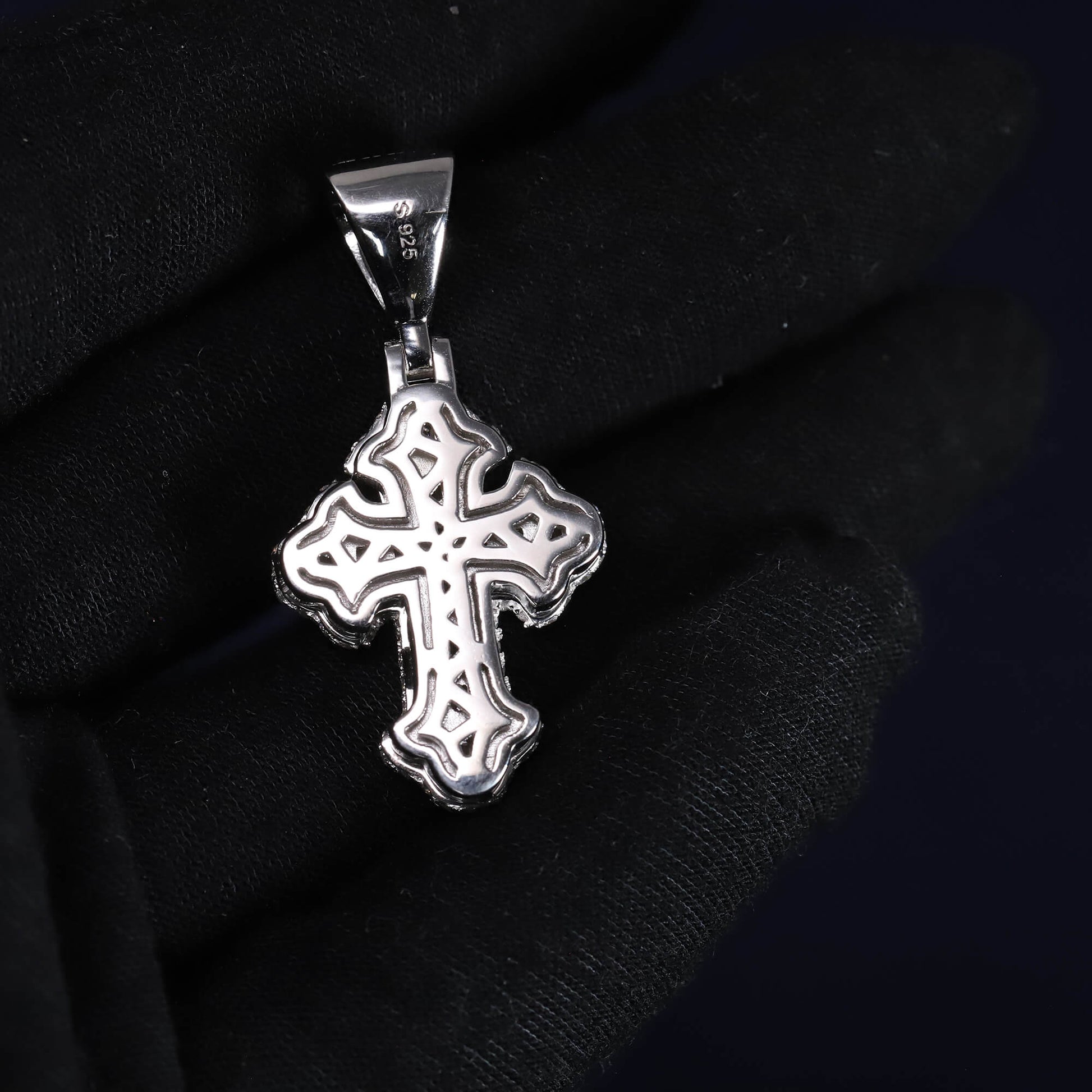 Silver cross pendant on a black fabric background