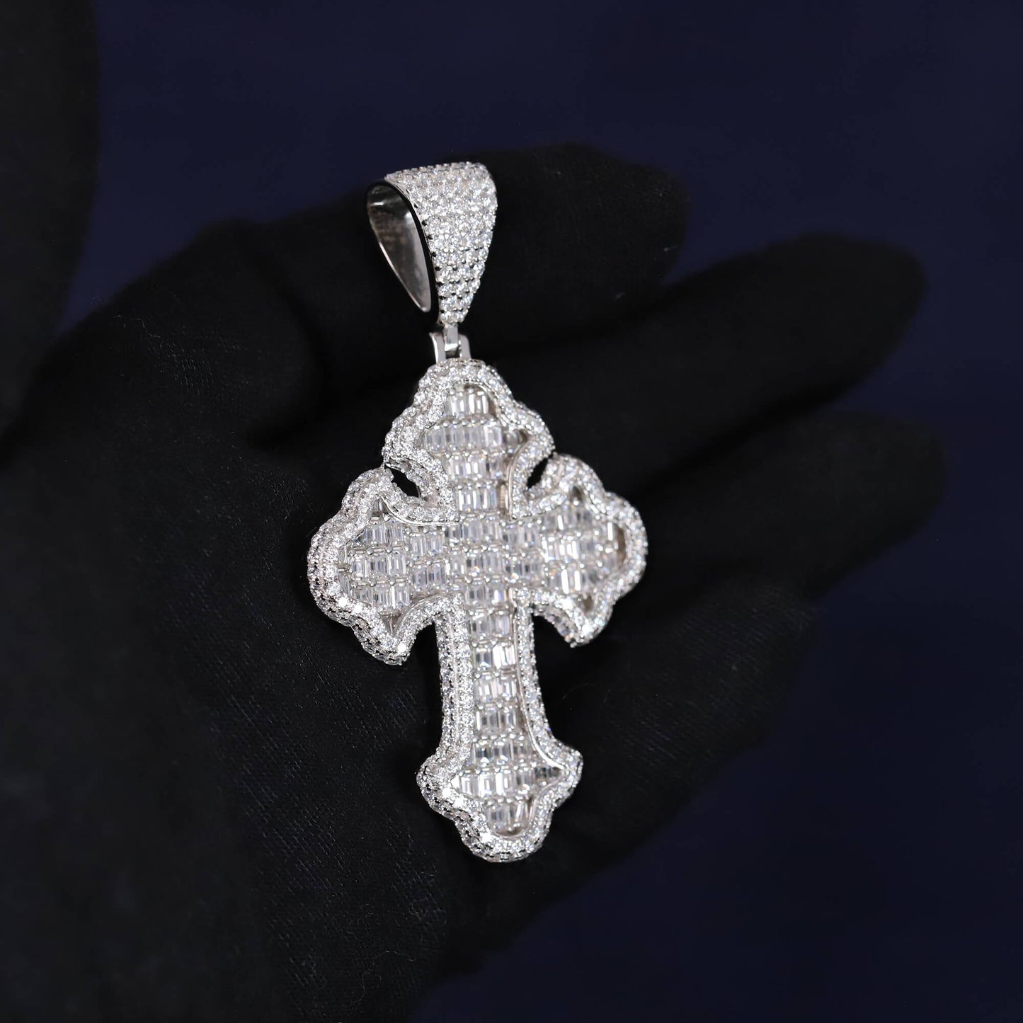 Silver cross pendant with clear stones on a dark background