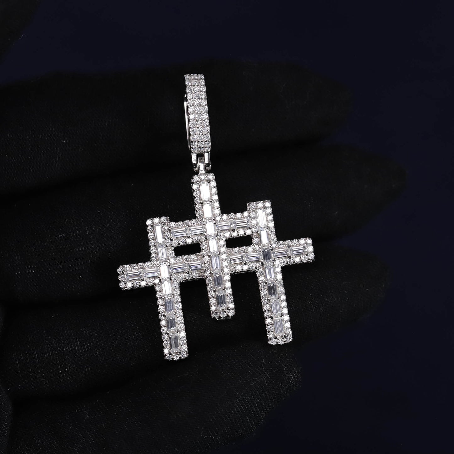 Silver cross pendant with clear stones on a black background