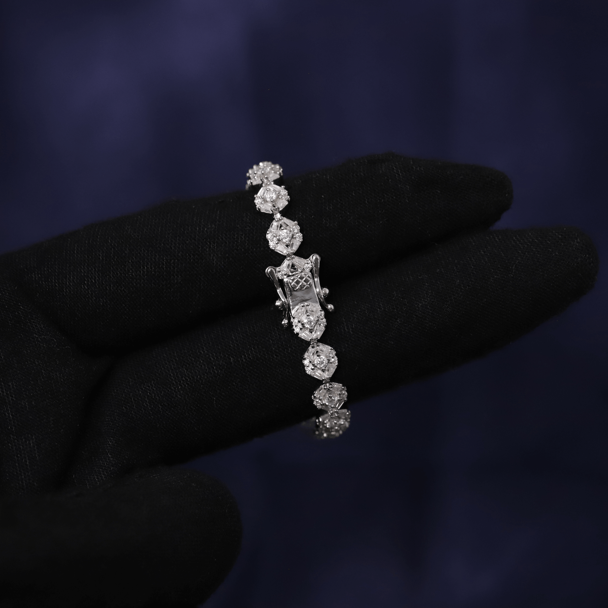 Diamond bracelet held by a gloved hand against a dark background