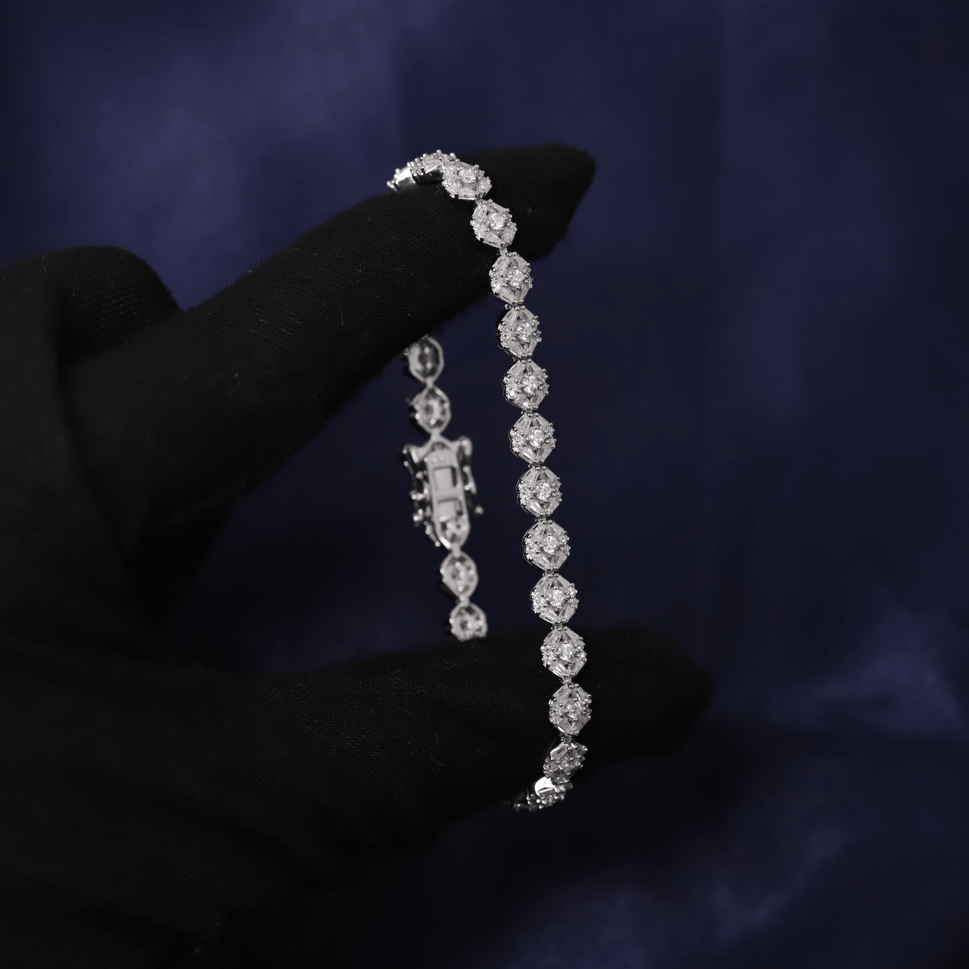 Diamond bracelet held by a hand against a dark background