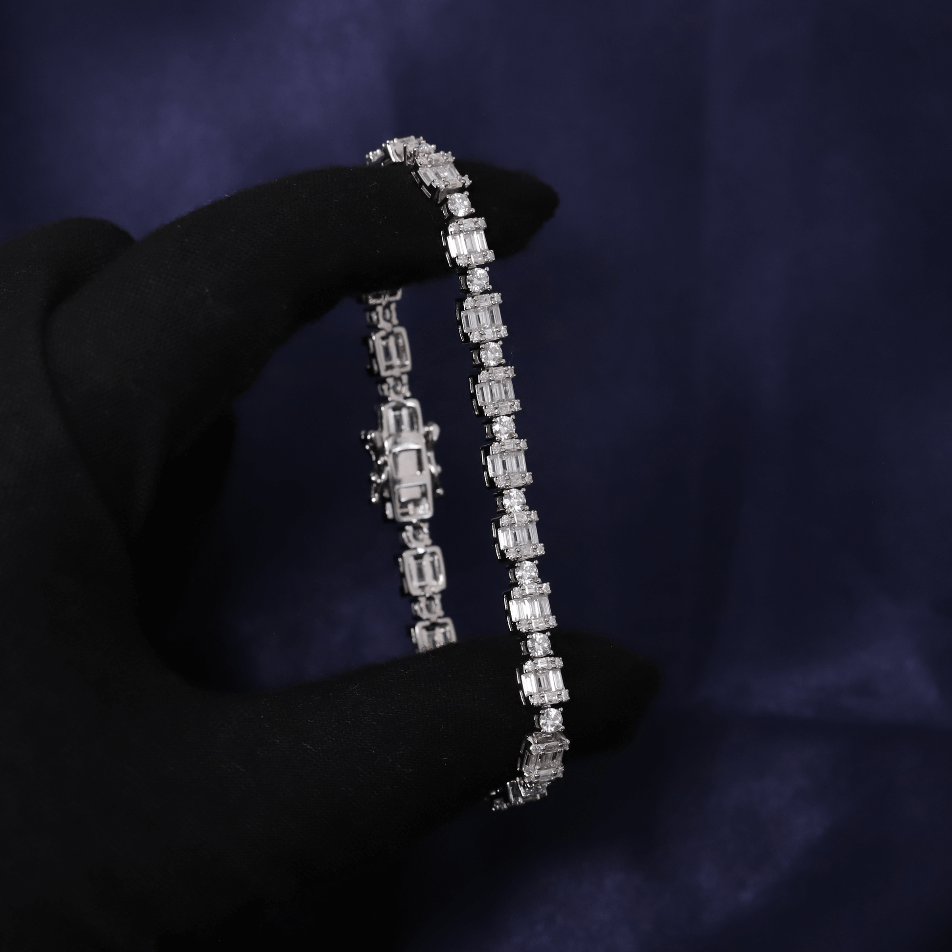 Diamond bracelet held by a gloved hand against a dark background