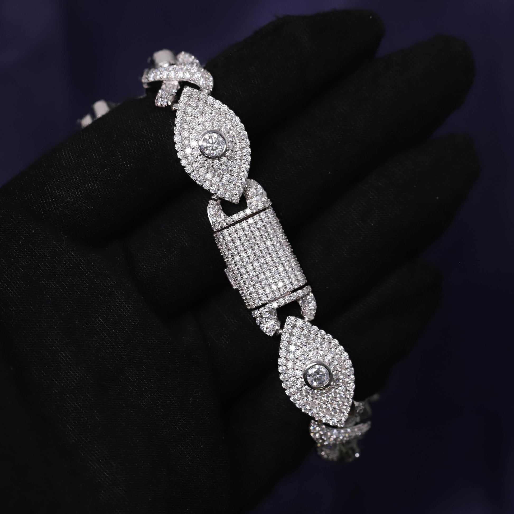 Silver bracelet with diamond accents on a black glove against a dark background