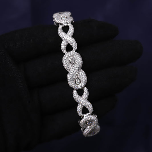 Silver bracelet with intricate design held by a gloved hand against a dark background