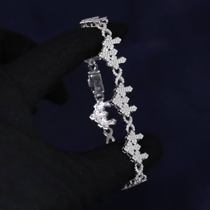 Silver bracelet with floral design held by a gloved hand against a dark background