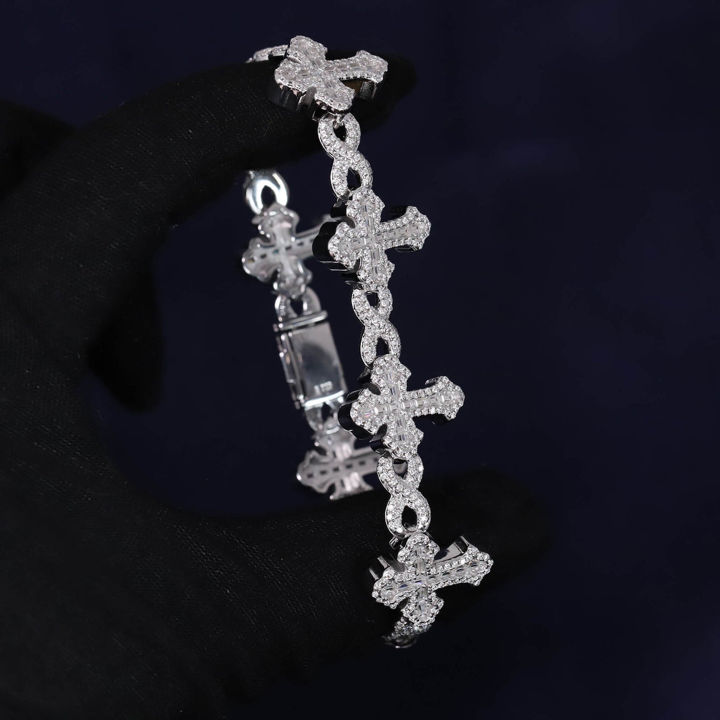 Silver cross-shaped bracelet with clear stones on a dark background