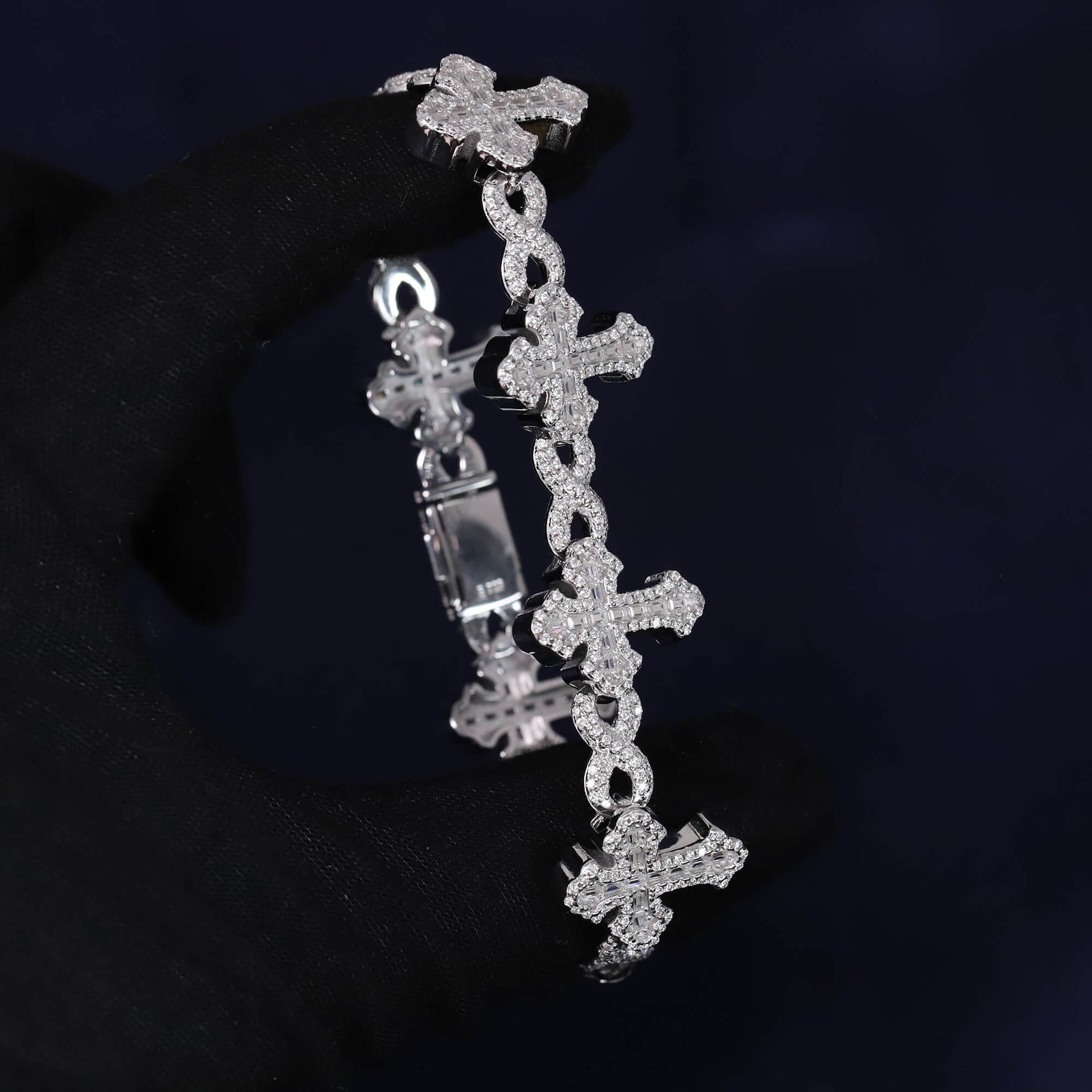 Silver cross-shaped bracelet with clear stones on a dark background