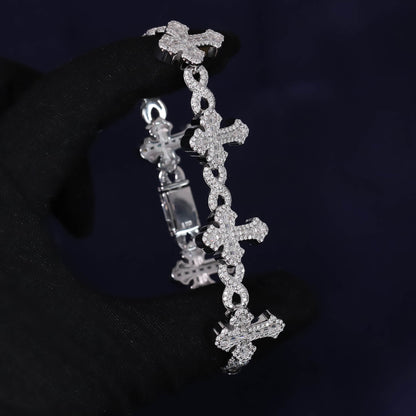 Silver cross-shaped bracelet with clear stones on a dark background