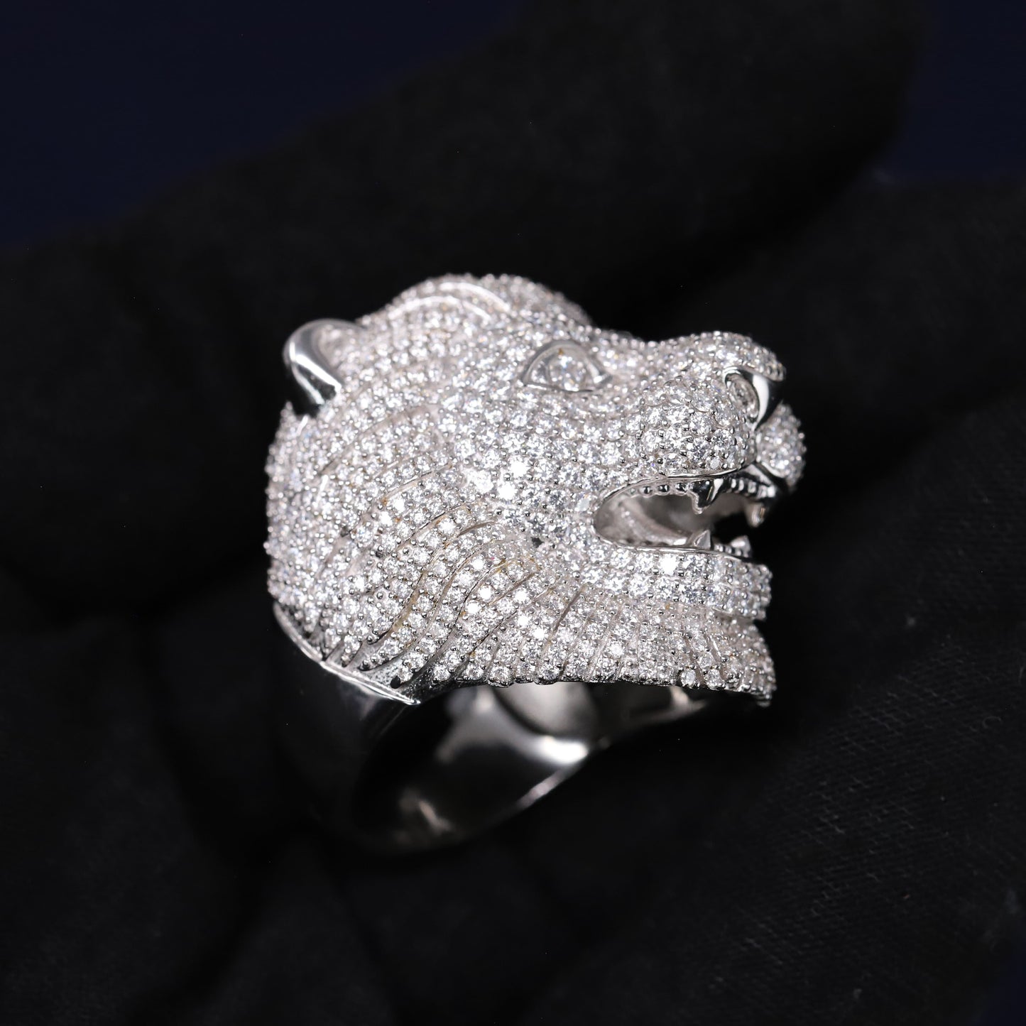 Silver panther head ring with gemstones on a black background
