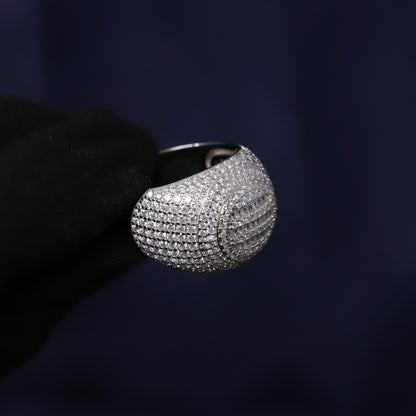 Silver ring with gemstones held by a black gloved hand against a dark background
