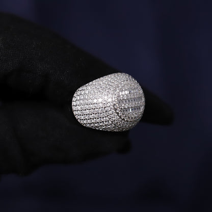 Silver ring with diamonds held by a gloved hand against a dark background
