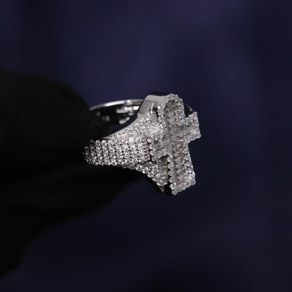 Silver cross-shaped ring with embedded stones on a dark background