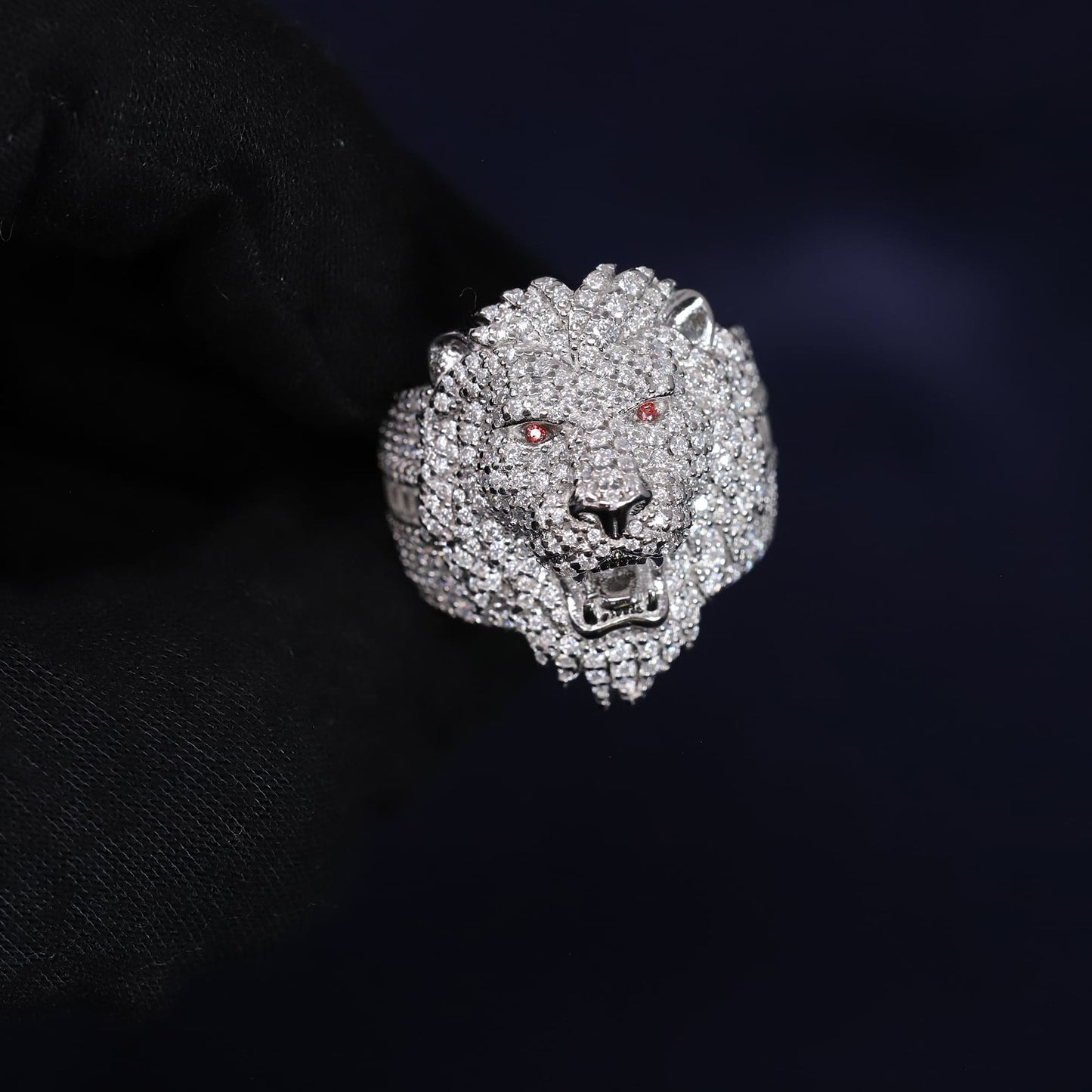 Silver lion head ring with gemstones on a dark background