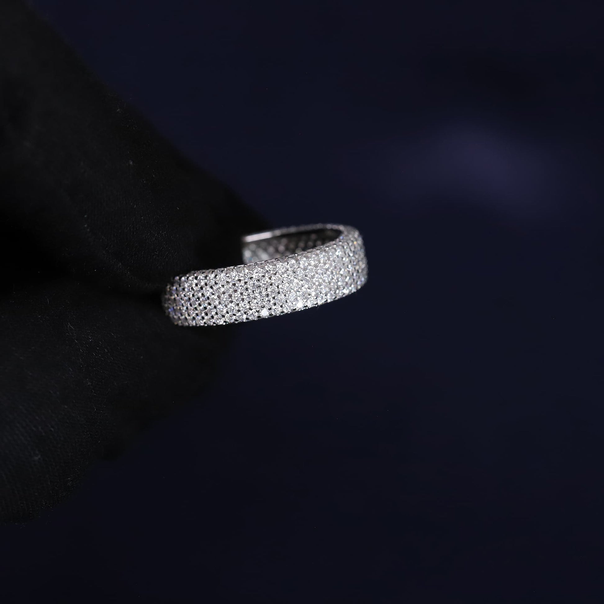 Silver ring with embedded stones on a dark background