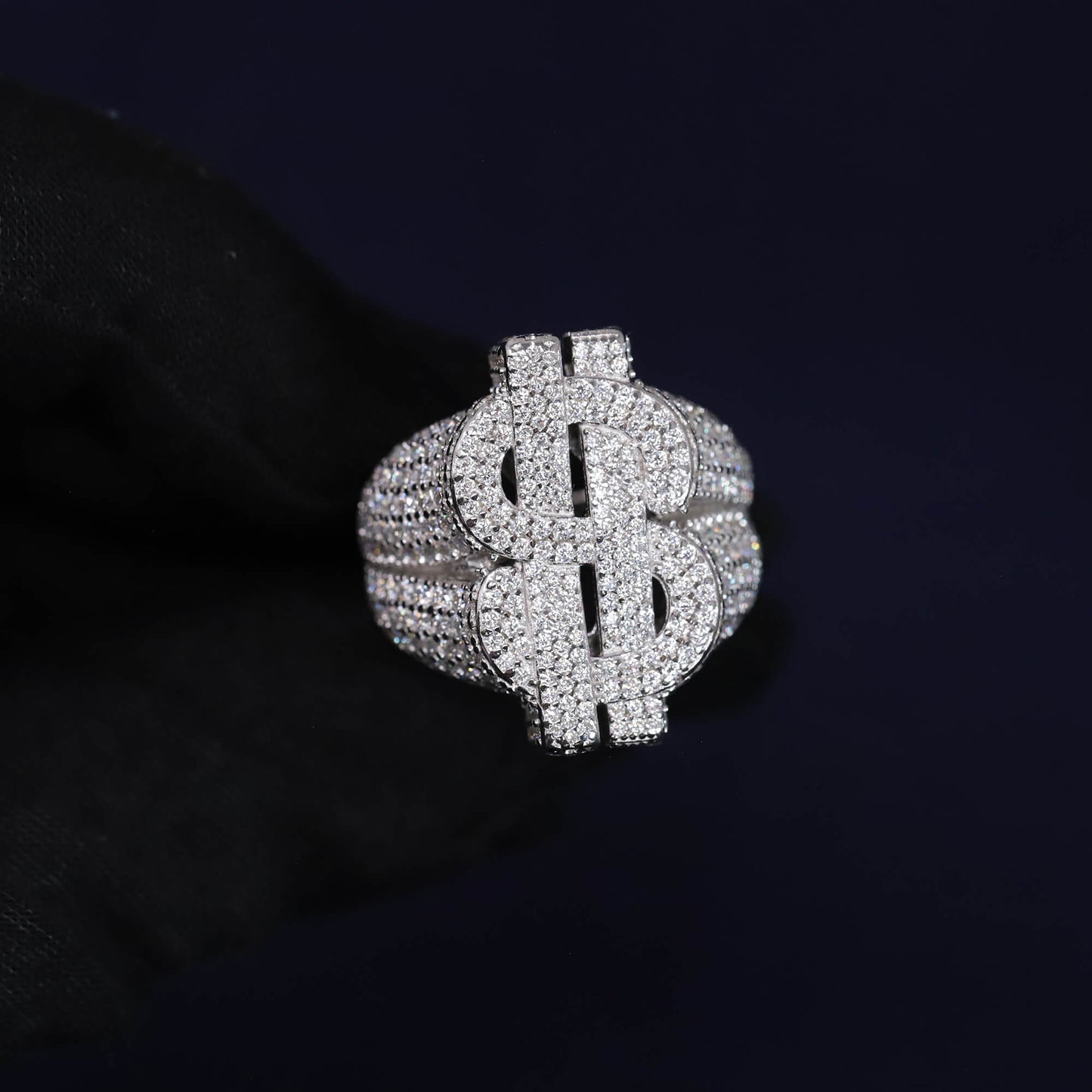 Silver dollar sign ring with clear stones on a black background