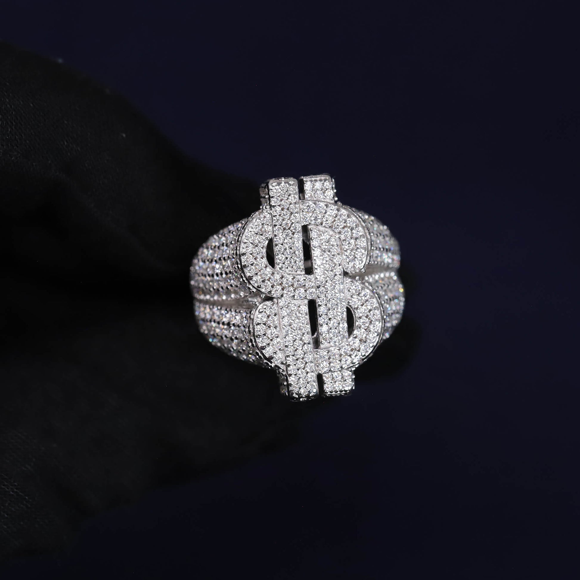 Silver dollar sign ring with clear stones on a black background