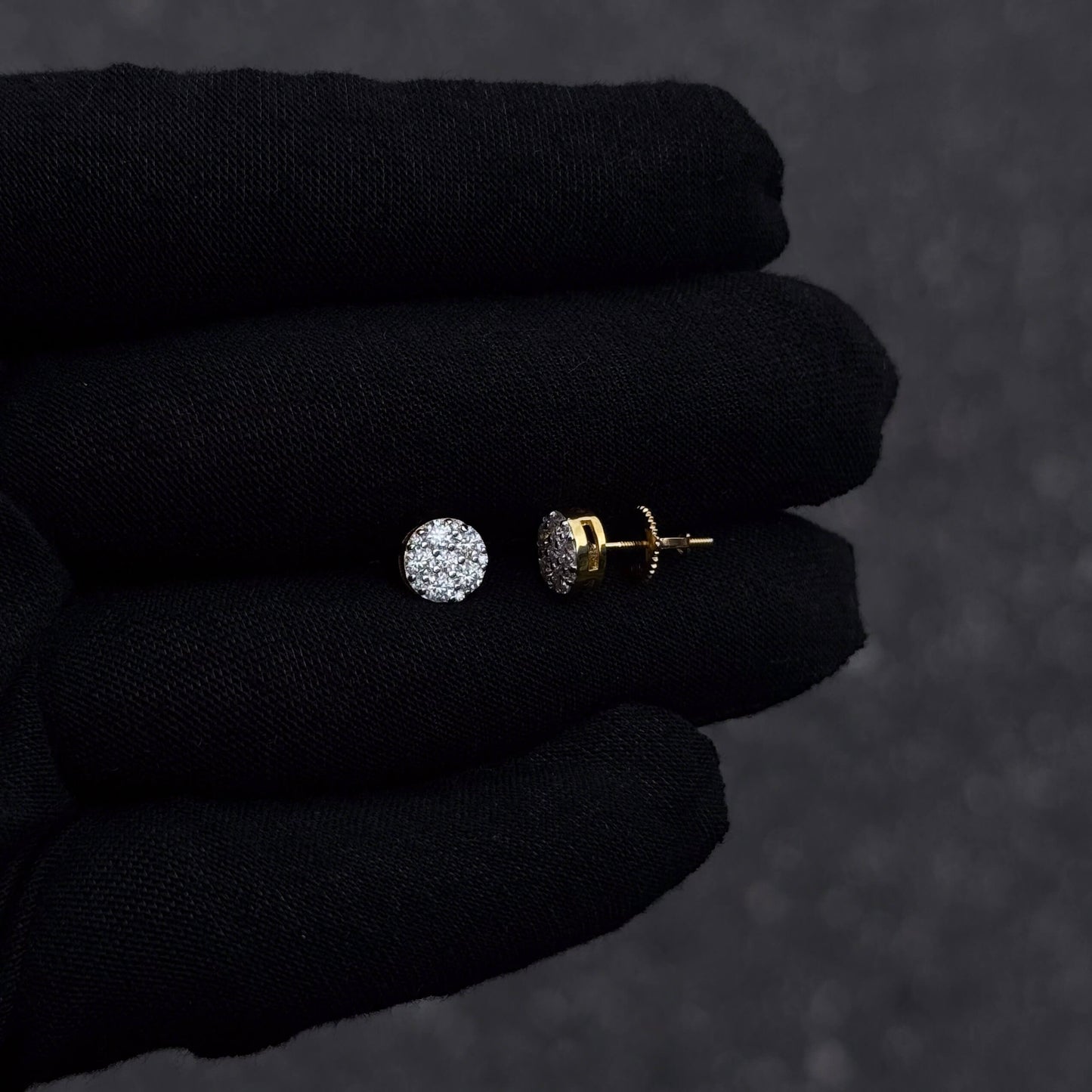 Gold-plated 7mm round moissanite cluster diamond stud earrings with screw backs shown on black glove.