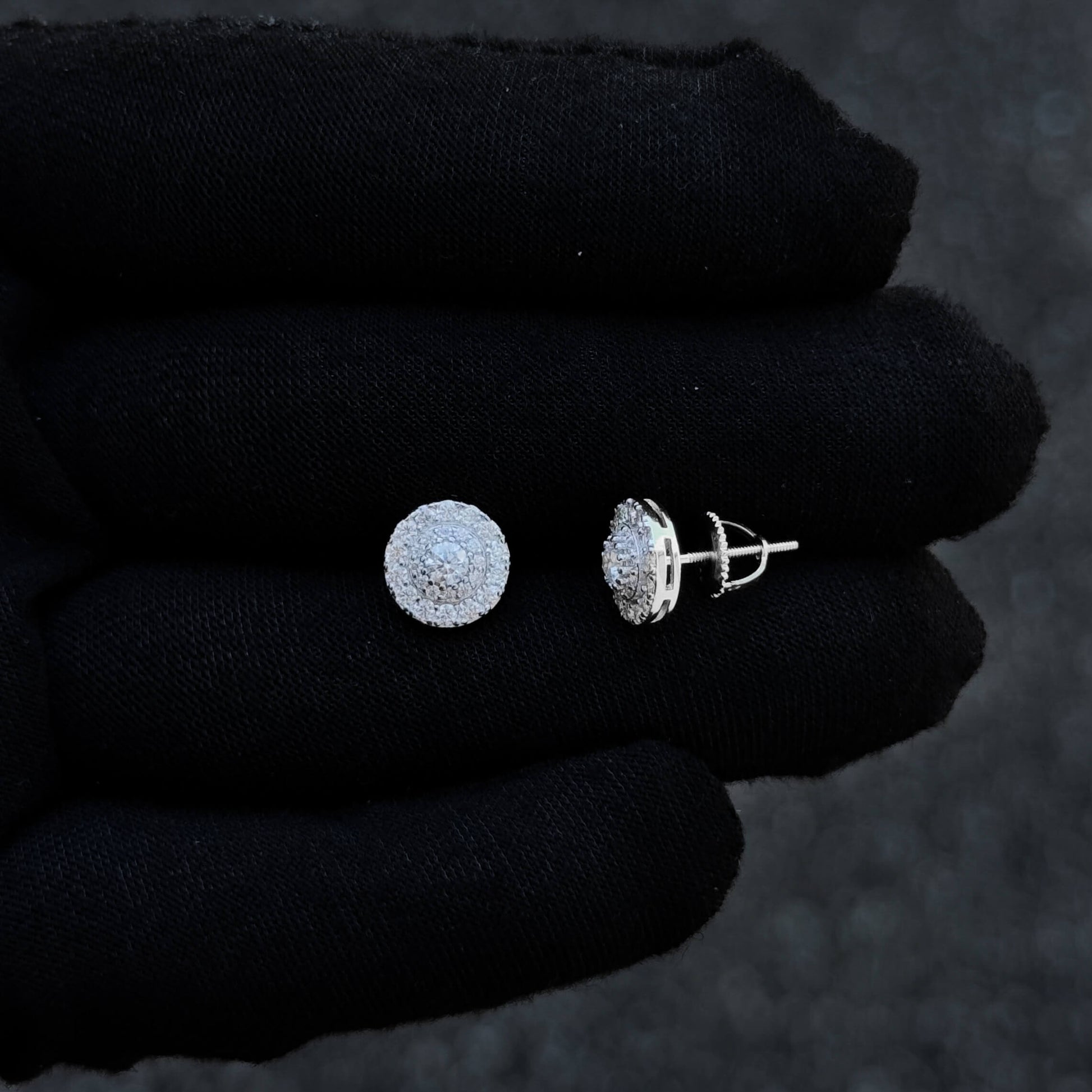 Sterling silver 9mm moissanite cluster earrings shown on black glove with halo design.