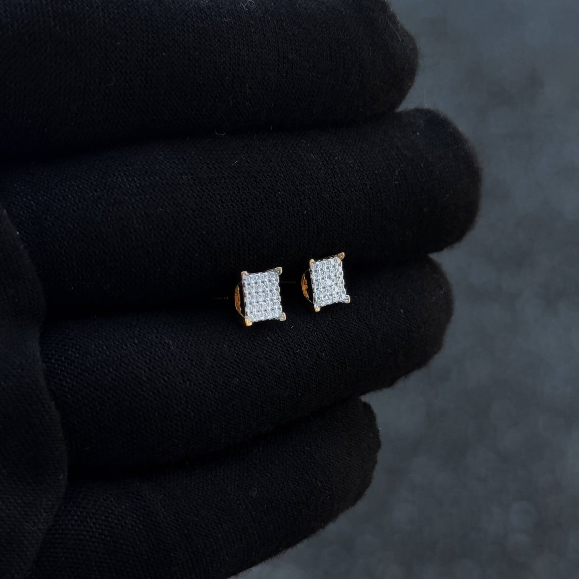 Gold-accent 6mm square Moissanite cluster earrings displayed at an angled view on black glove.