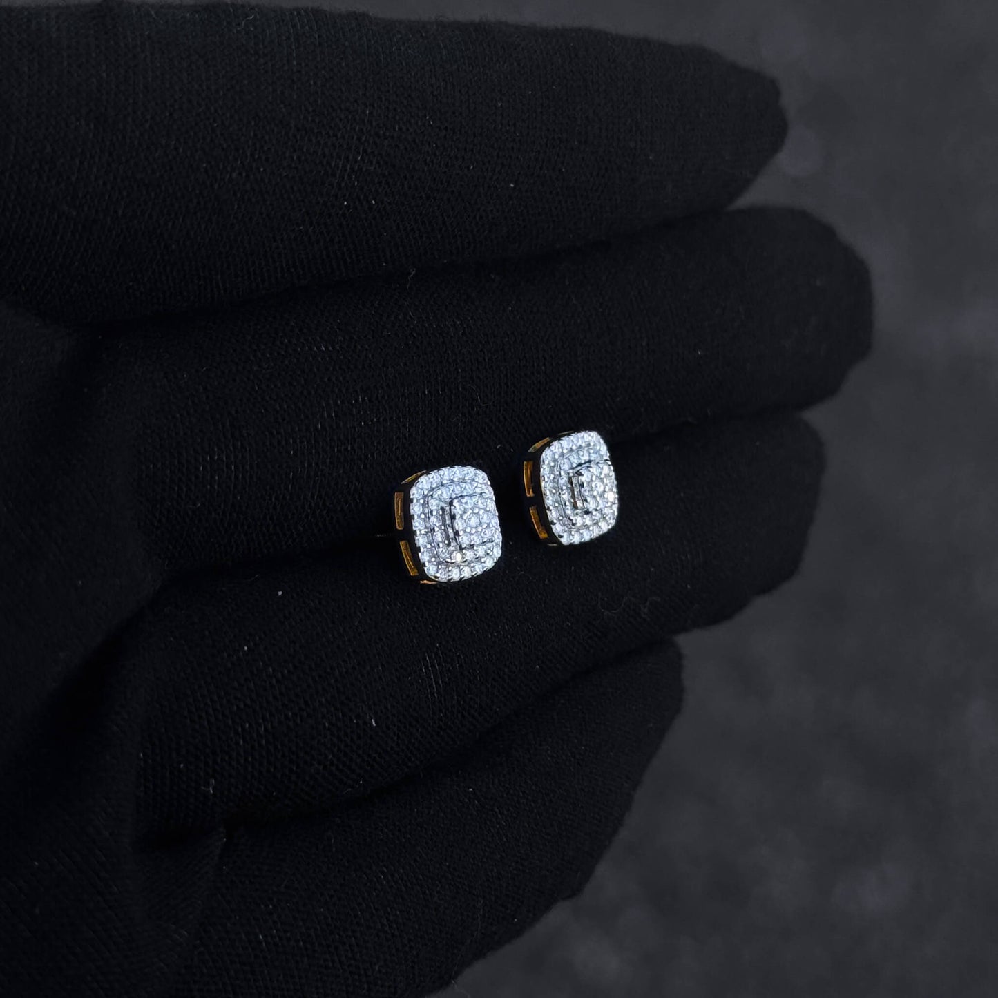 Gold-trim square moissanite cluster earrings shown on black glove, featuring triple halo diamond detail.
