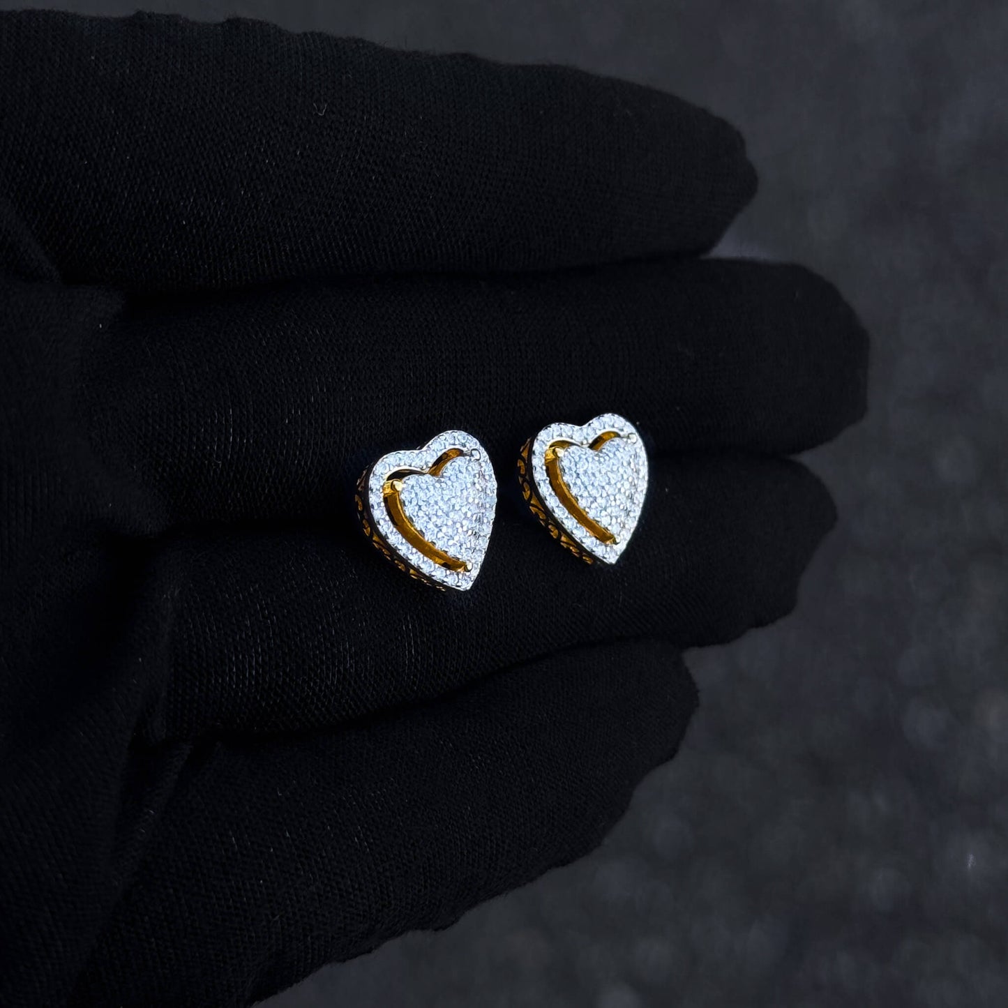 Gold heart moissanite cluster stud earrings shown on black glove with pavé detailing.