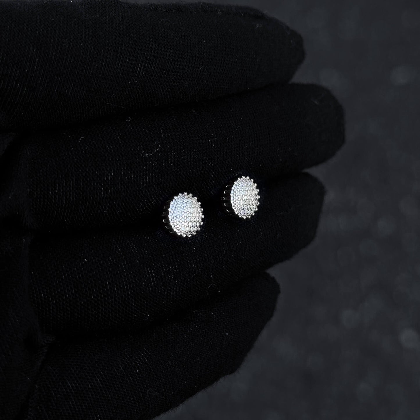 Sterling silver 8mm moissanite cluster earrings with bright diamond sparkle on glove display.