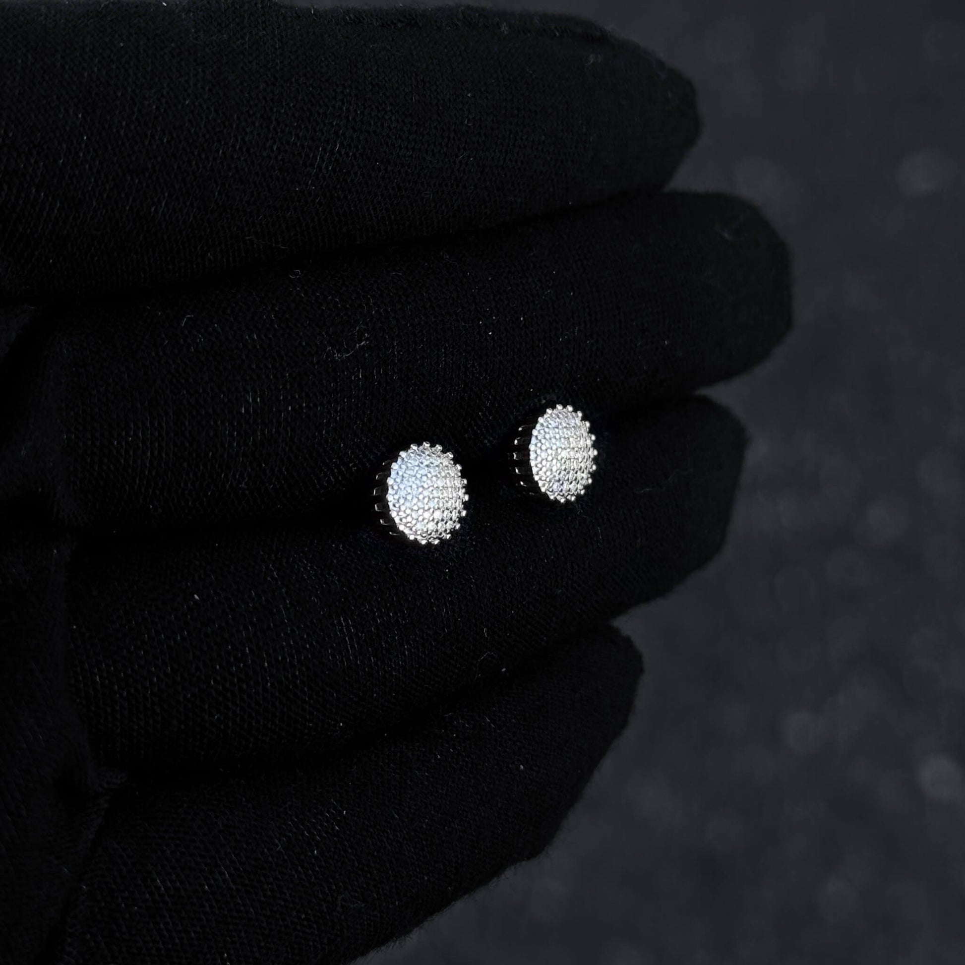 Sterling silver 8mm moissanite cluster earrings with bright diamond sparkle on glove display.