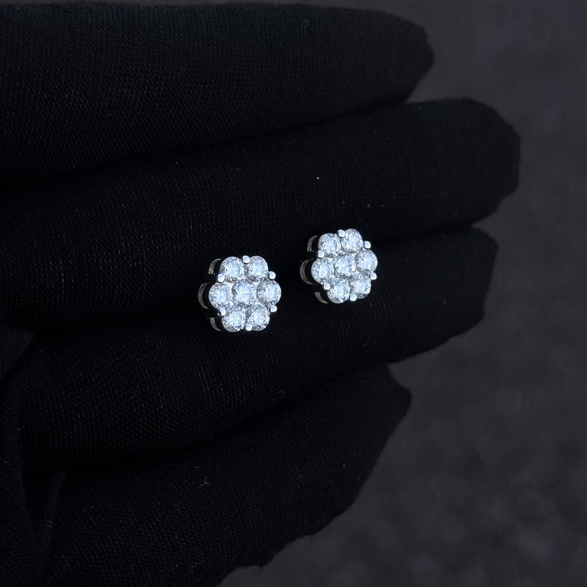 Sterling silver 10mm moissanite cluster diamond studs shown on black glove in angled view.
