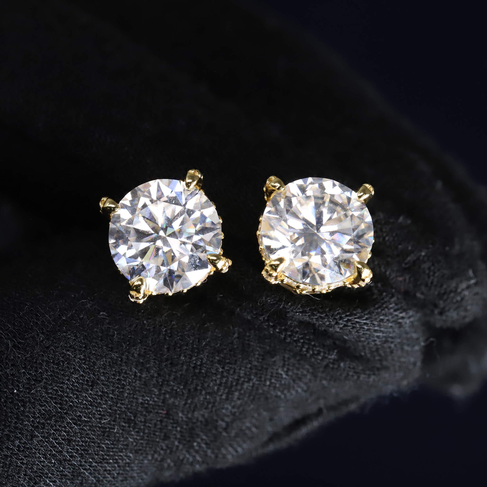 Gold stud earrings with clear gemstones on a black background
