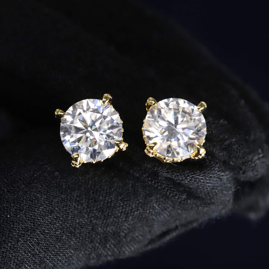 Gold stud earrings with clear gemstones on a black background