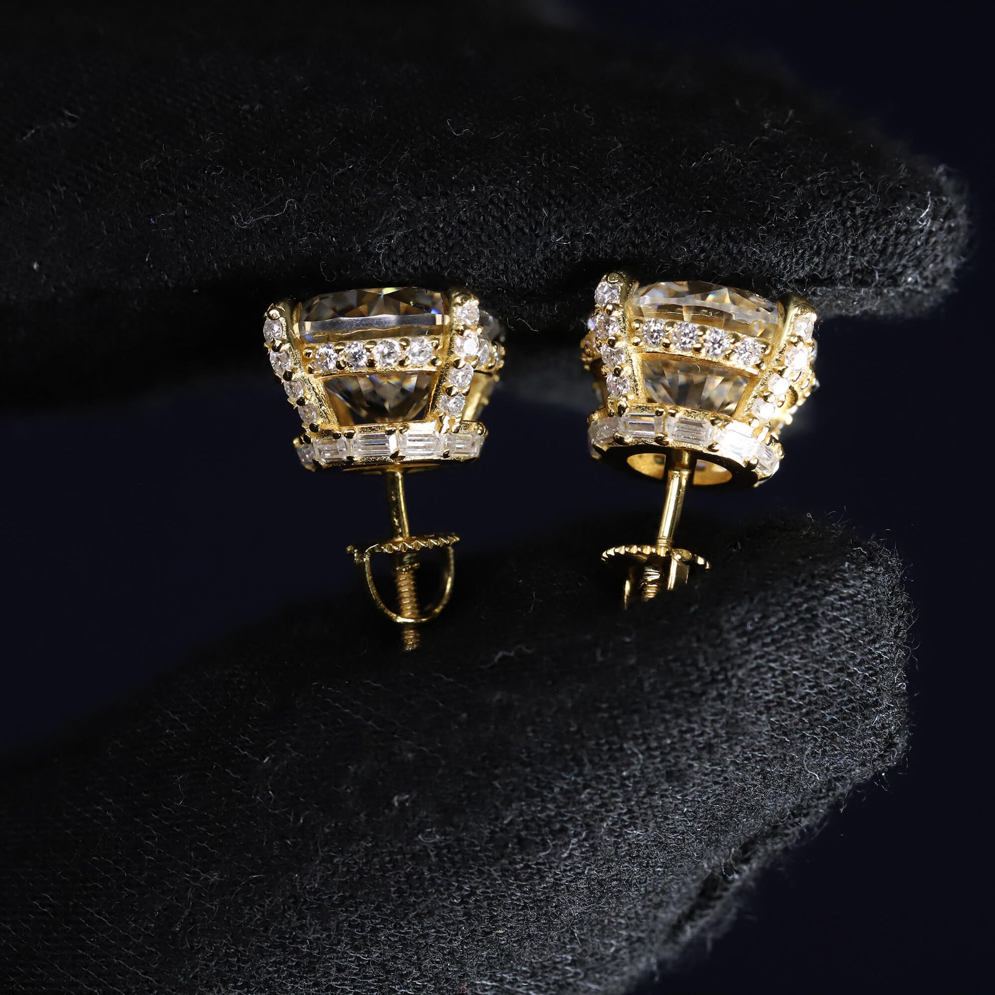 Gold earrings with clear gemstones on a black background